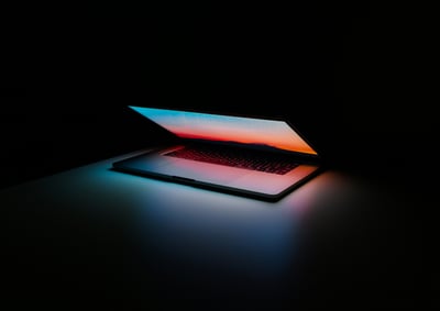a laptop glows in a dark room, half open