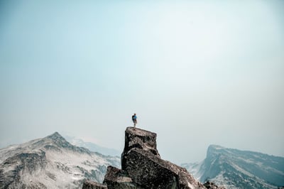 a climber at the top of a mountain looking out on the view