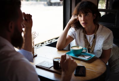 Woman listens to a man talking in cafe